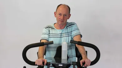 Michael Dann Larsen står ved staabordet i Specialhospitalet for Polio- og Ulykkespatienters traeningssal. Han er lam i benene, saa det er en kaerkommen lejlighed til at komme op af koerestolen og op at staa.